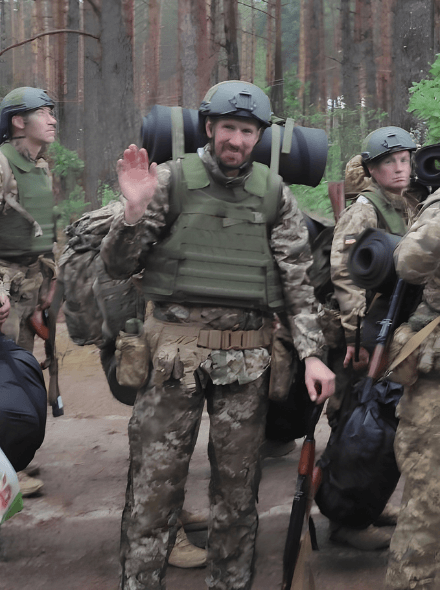 Tara in army gear in the woods amoung other service members.