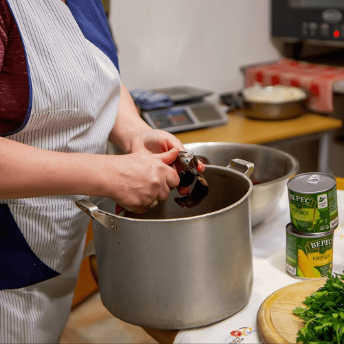 Svitlana prepares ingredients in a church kitchen in Ukraine, cutting vegetables and cooking food that will be served to families and volunteers through local humanitarian ministry efforts.
